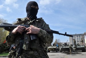 Armed men wearing military fatigues gather by Armored Personnel Carriers (APC) as they stand guard outside the regional state building seized by pro-Russian separatists in the eastern Ukrainian city of Slavyansk on April 16, 2014.